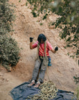 WILD Dirt worn by a climber handling rope with zero drop outdoor grippy outsole and adventurous aesthetic standing on a rocky climbing spot