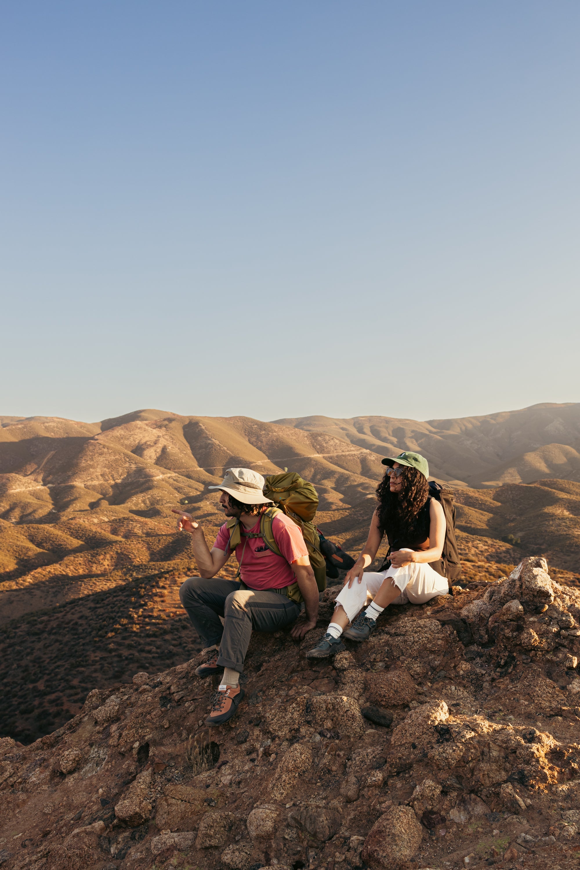 WILD Kai Hanging Out Hikers resting on a rocky mountain ridge wearing LONO WILD barefoot hiking shoes with wide toe box comfort